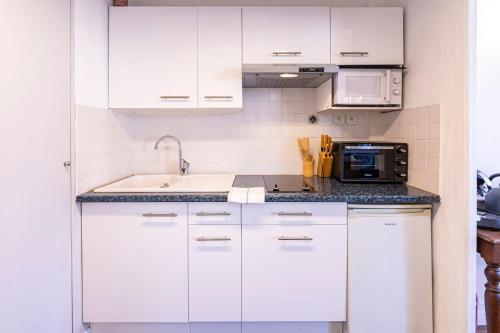 une cuisine blanche avec un évier et un micro-ondes dans l'établissement La Suite Matisse 700m centre-ville, à Angers