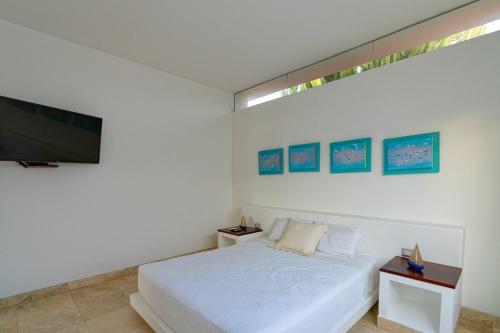 a white bedroom with a bed and a flat screen tv at Casa Wayta in Los Órganos