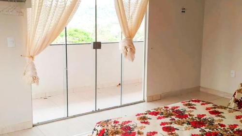 a bedroom with a bed and a large window at Chalé Confortável e Completo com piscina in Roças Novas