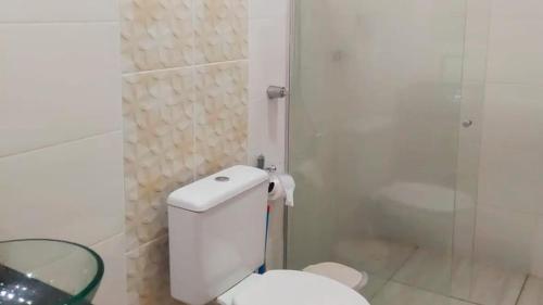 a white bathroom with a toilet and a shower at Chalé Confortável e Completo com piscina in Roças Novas