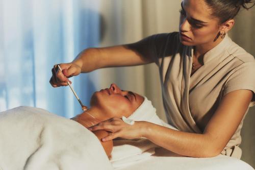 a woman injecting a patient with a needle at Hôtel Plage Palace & Spa in Palavas-les-Flots
