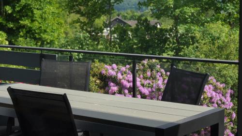 einen Tisch und Stühle auf einem Balkon mit Blumen in der Unterkunft Ferienhaus Magnolie in der Eifel in Monschau