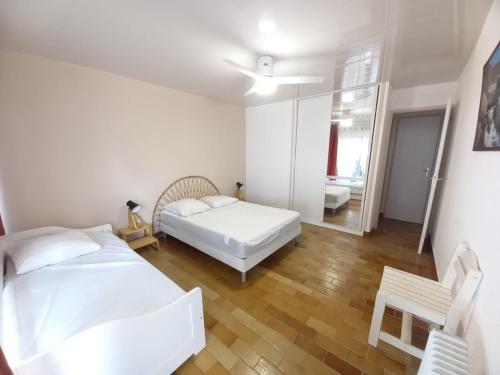 une chambre avec deux lits et un miroir dans l'établissement T2 familial 1ère ligne plages Parking privé WIFI - Le Foc - ROSSIconciergerie - Linge en option, au Grau-du-Roi