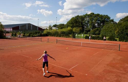 three people playing tennis on a tennis court at SCHLOSS Fleesensee in Göhren-Lebbin