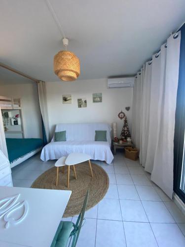 - une chambre avec un lit blanc, une table et un tapis dans l'établissement Appartement vue mer, au Barcarès