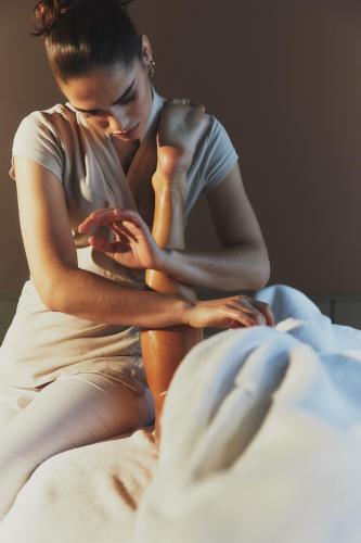 a woman sitting on a bed looking at her cell phone at Hôtel Plage Palace & Spa in Palavas-les-Flots
