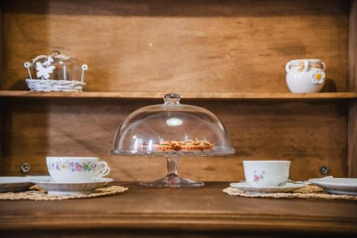 a glass cloche sitting on a shelf with two cups at B&B Terra - Stanza Natura in Carloforte
