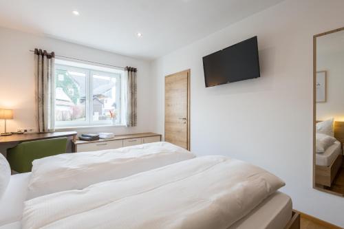 a bedroom with a white bed and a television on the wall at Pension Zum Schrammel in Altdorf bei Nuernberg