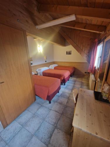 a room with two beds and red couches at Hotel Raibl e Appartamenti in Tarvisio