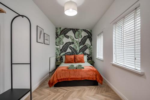 a bedroom with a bed with orange sheets and a plant mural at Stylish 2 Bedroom Apartment in Belfast in Belfast
