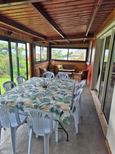 a dining table and chairs on a screened porch with a table and chairs at le ti coin papi hugues in La Plaine des Palmistes