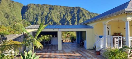 a house with a porch with a mountain in the background at le ti coin papi hugues in La Plaine des Palmistes
