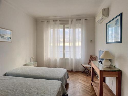 une chambre avec deux lits et un bureau et une fenêtre dans l'établissement Situation et vue mer exceptionnelle 62L, à Cannes