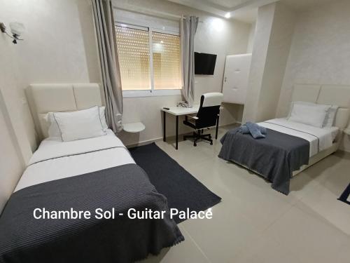 a hotel room with two beds and a desk at GUITAR PALACE - Chambres d'hôtes in Bni Quolla