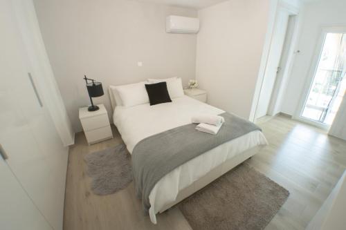 a white bedroom with a large bed and a wooden floor at Luxury 2 storey 2bedroom condo with Private Jacuzzi & patio - Athens in Athens