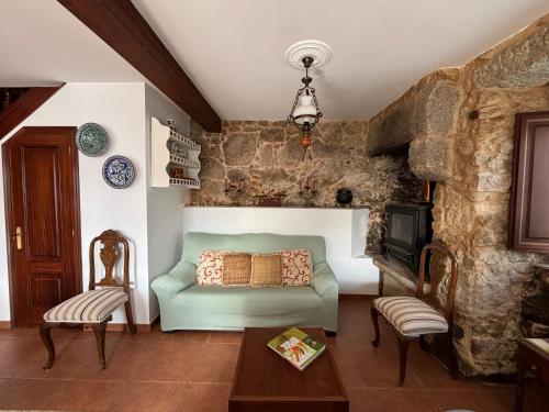 a living room with a green couch and a stone wall at Casa Martorell Ferrol in Ferrol