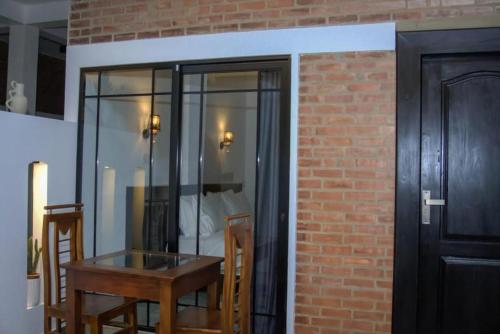 a dining room with a table and a brick wall at Rome Transit Hotel in Negombo