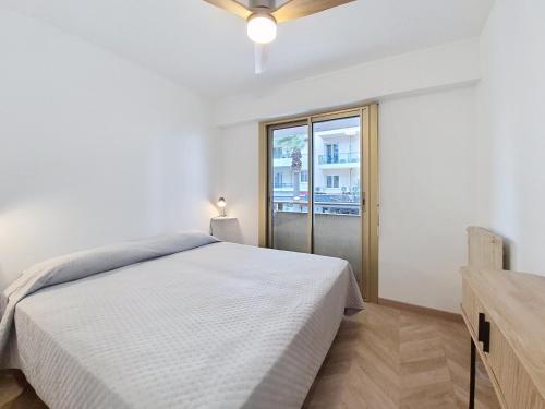 a white bedroom with a bed and a window at Bleu de Juan in Antibes