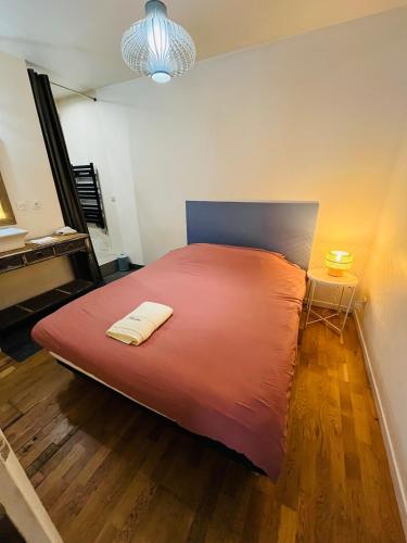 une chambre avec un grand lit avec une couverture rouge dans l'établissement Le Pont Péri, à Bourg-lès-Valence