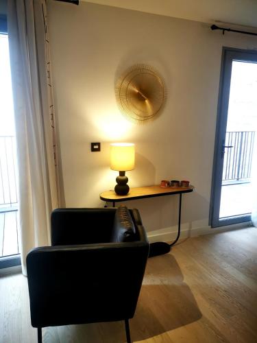 un salon avec une chaise et une table avec une lampe dans l'établissement Toulouse, Bourse nice and comfortable family apartment, à Toulouse
