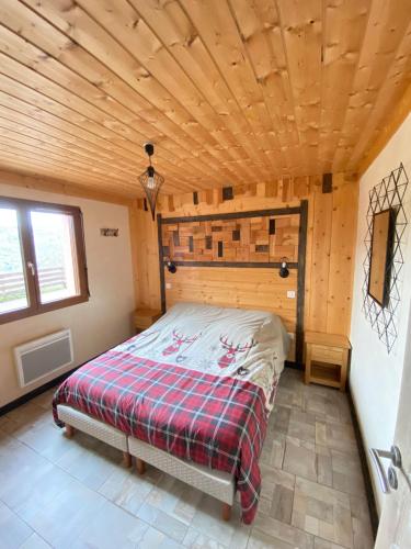 un lit dans une chambre avec un plafond en bois dans l'établissement LE GRENIER DES MIOS, à La Bresse