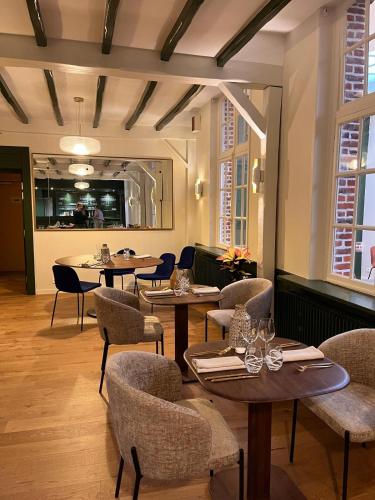 a restaurant with tables and chairs in a room at Logis - Hostellerie Saint-Louis & Restaurant Pauze in Bollezeele