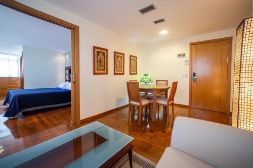 a living room with a bed and a table and chairs at Hotel Auditorio Santiago & Spa in Lugo