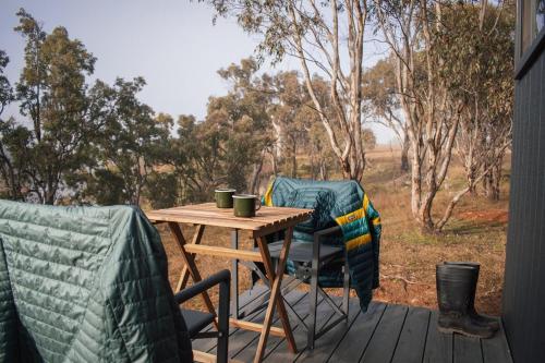 a table and two chairs on a deck with a table at Secluded Off-Grid Cabin Lake View - Pet Friendly - Mateo in Rylstone