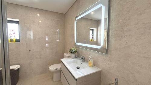 un bagno con lavandino, WC e specchio di Casa da Praia, piscina a sal, aquecida e coberta -Praia da Barra a Praia da Barra