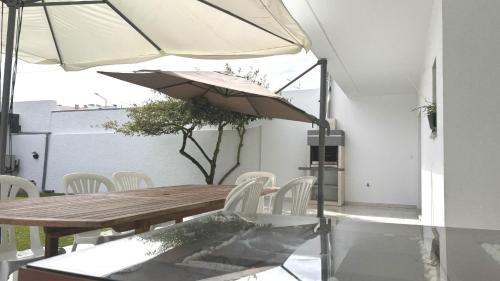 a wooden table and chairs with an umbrella at Casa da Praia, piscina a sal, aquecida e coberta -Praia da Barra in Praia da Barra