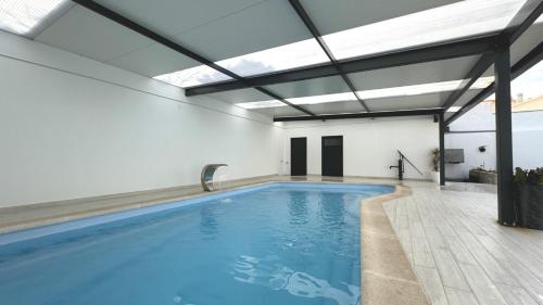 an indoor swimming pool with blue water in a building at Casa da Praia, piscina a sal, aquecida e coberta -Praia da Barra in Praia da Barra