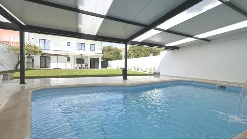 a swimming pool in a house with an open ceiling at Casa da Praia, piscina a sal, aquecida e coberta -Praia da Barra in Praia da Barra