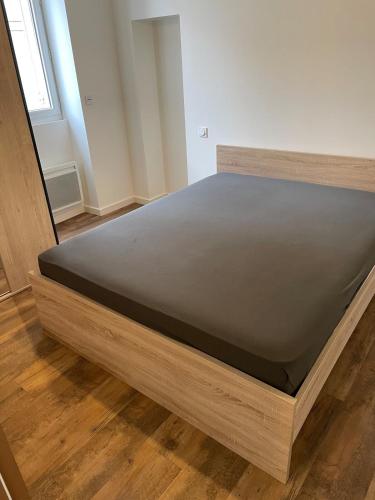 Ce lit se trouve dans un dortoir doté d'un cadre de lit en bois. dans l'établissement Coeur de ville, à Périgueux