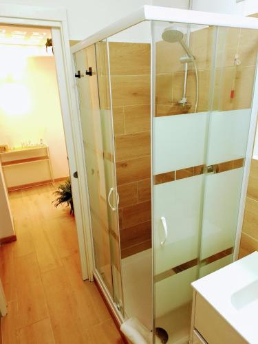 a glass shower stall with a mirror in a bathroom at Elunà Assisi Home in Assisi