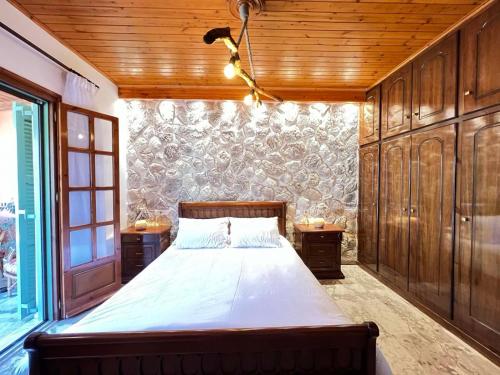 a bedroom with a large bed and wooden walls at Villa Yiannitsis-Harmony In The Flowers, Acharavi Beach in Litherés