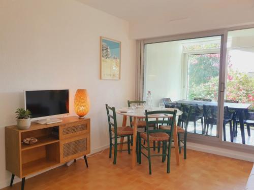 une salle à manger avec une table, des chaises et une télévision dans l'établissement T2 traversant familial CAP SUD Parking Plages - ROSSIconciergerie - Linge en option, à La Grande Motte