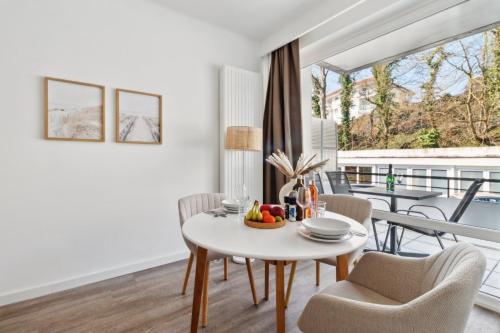 a white dining room with a table and chairs and a balcony at Beachside Grömitz - 21 Apartments, Pool & Sauna direkt am Meer in Grömitz