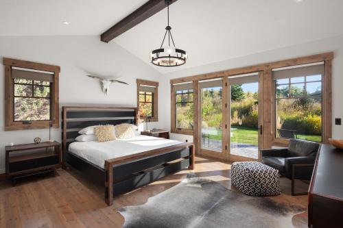 a bedroom with a bed and a chair and windows at Lodge at Whitefish Lake in Whitefish