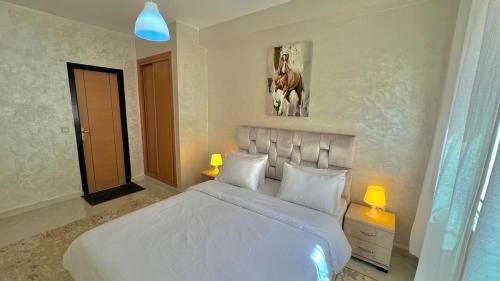 a bedroom with a large white bed with two lamps at T6 Luxury in Témara Discover a Comfortable Apartment in Temara