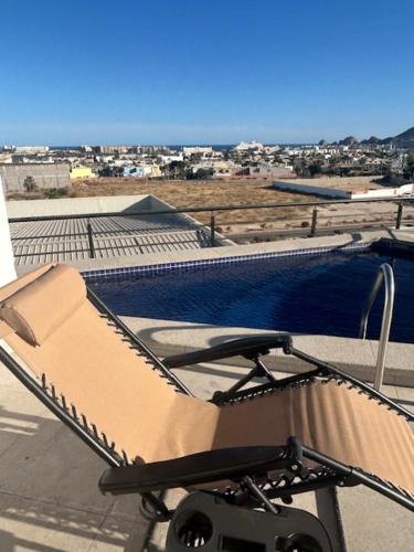 a chair on top of a roof with a pool at Cabo Manor - Boutique Condo in Cabo San Lucas