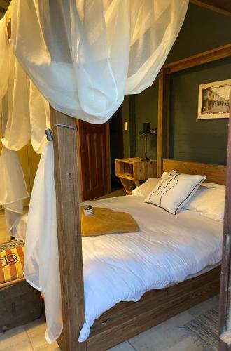 a bedroom with a canopy bed with white curtains at Studio 101 in Oudtshoorn