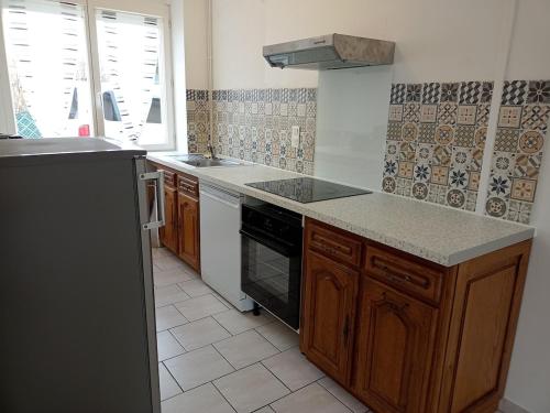 une cuisine avec un évier et une cuisinière four supérieur dans l'établissement L'atelier du bord de mer - Pourville-sur-Mer, à Hautot-sur-Mer