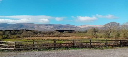 a wooden fence in a field with mountains in the background at Luxury Studio Stunning Views - Milltown in Milltown