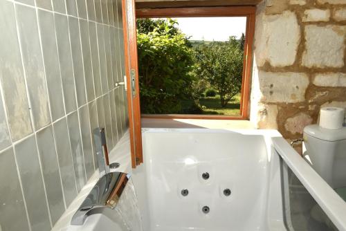 une salle de bain avec baignoire et toilettes et une fenêtre dans l'établissement Charmante maisonnette au calme, à Vadencourt-et-Bohéries