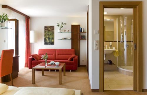 a living room with a red couch and a table at Landgasthof Zur schönen Wienerin in Marbach an der Donau
