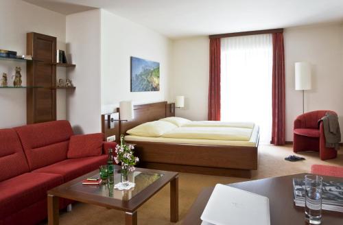 a living room with a bed and a red couch at Landgasthof Zur schönen Wienerin in Marbach an der Donau