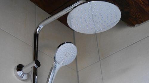 a shower head and a mirror in a bathroom at Pension & Café Schlupfwinkel in Salem