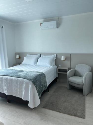 a bedroom with a bed and a chair at Hospedaria da Vó Sandra in Treze Tílias