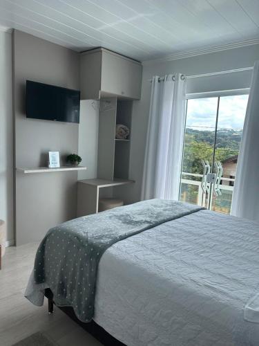 a bedroom with a bed and a large window at Hospedaria da Vó Sandra in Treze Tílias