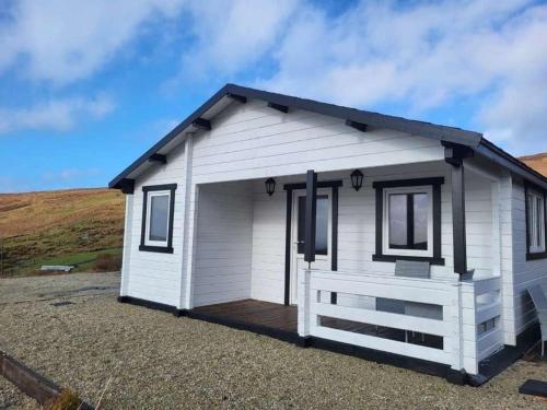 a white tiny house with a porch at Hillside Hideaway in Doonalt